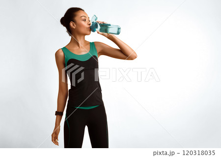 Workout Lifestyle. Black Woman In Sportswear Drinking Water Standing Over Yellow Background In Studio. Empty Space For Text Workout Lifestyle. Black Woman In Sportswear Drinking Water Standing Over Yellow Background In Studio. Empty Space For Text 120318035