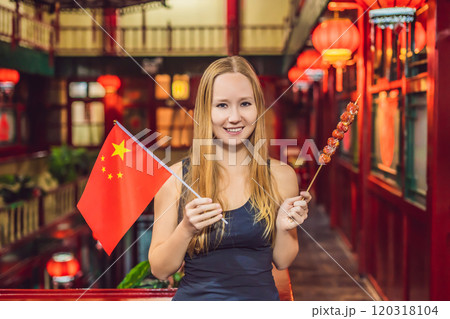 Enjoying vacation in China. Happy woman tourist with a Chinese flag and with traditional Chinese candied fruits on a Chinese background. Travel to China concept. Visa free transit 72 hours, 144 hours Enjoying vacation in China. Happy woman tourist with a Chinese flag and with traditional Chinese candied fruits on a Chinese background. Travel to China concept. Visa free transit 72 hours, 144 hours 120318104