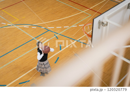学校の体育館でバスケットボールをする女子学生 120320779