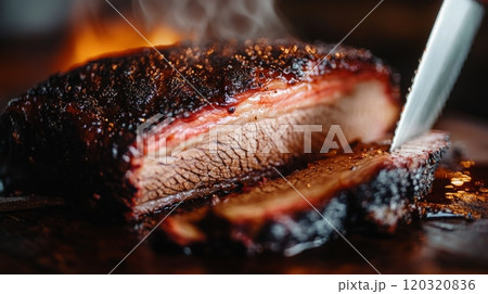 A succulent smoked brisket is sliced on a wooden board, revealing its tender texture and smoky flavor, while flames flicker in the background, enhancing the grilling atmosphere. 120320836