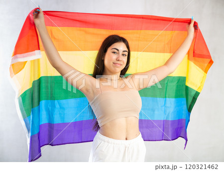 Happy young woman with LGBT flag against unicoloured wall 120321462