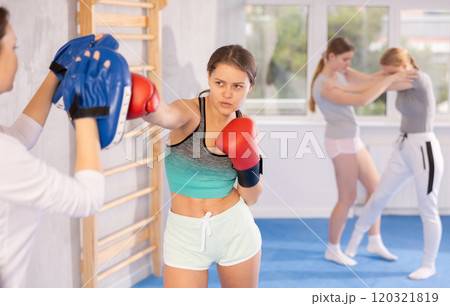 Teen girl in punch mitts boxing 120321819