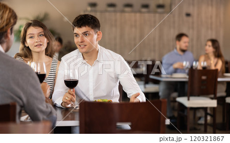 Couple and adult man eating and talking in restaurant Couple and adult man eating and talking in restaurant 120321867