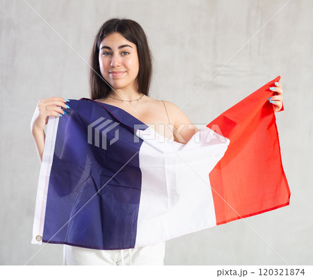 Happy young woman with flag of France against unicoloured background 120321874