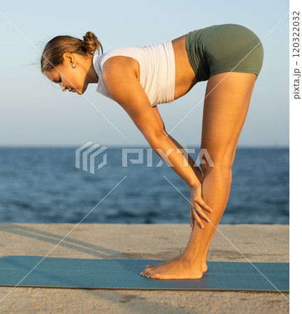 Yoga pose called uttanasana performed by a girl on seashore 120322032