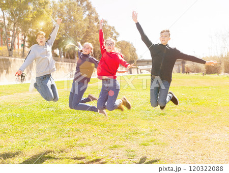 Cheerful teen friends jumping in city park Cheerful teen friends jumping in city park 120322088