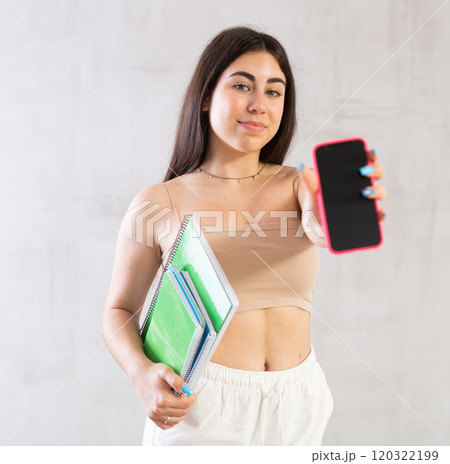 Young woman posing with stack of notebooks and phone in studio Young woman posing with stack of notebooks and phone in studio 120322199
