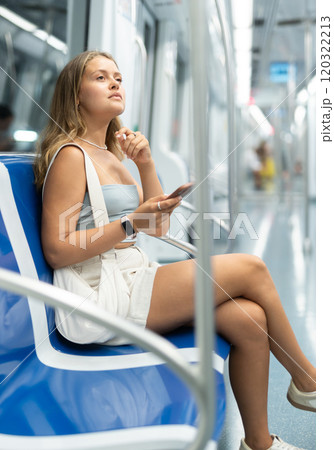Young girl sitting in wagon holding mobile phone in hand 120322213