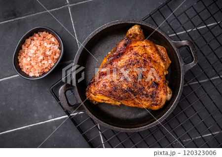 Fried roasted chicken thigh in a skillet, eco poultry meat. black background. top view Fried roasted chicken thigh in a skillet, eco poultry meat. black background. top view 120323006