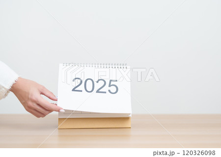 Business woman hand change 2025 Year Calendar on table in office background. countdown, Happy New Year, Resolution, Year End and New Start and Goals Plan Action Concept 120326098