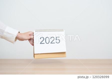 Business woman hand change 2025 Year Calendar on table in office background. countdown, Happy New Year, Resolution, Year End and New Start and Goals Plan Action Concept 120326099