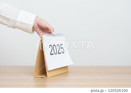 Business woman hand change 2025 Year Calendar on table in office background. countdown, Happy New Year, Resolution, Year End and New Start and Goals Plan Action Concept 120326100