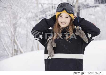 雪の降るスキー場で笑顔で立つスノボ女子 120326346