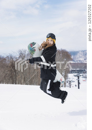 スキー場でジャンプをする若い女性 120327202