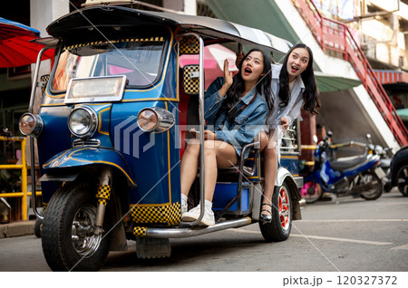Two excited Asian girls enjoy a ride in a tuk-tuk in Thailand, amazed by the stunning views. 120327372