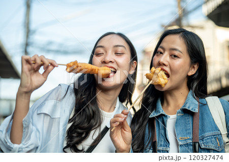 Two beautiful Asian female tourists are enjoy street food in Thailand while exploring the city. 120327474