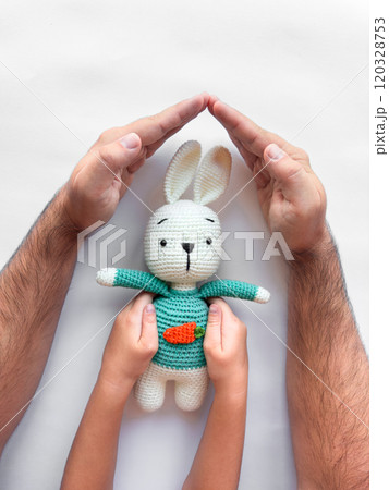 Parent and child hands cradling a knitted bunny with love and care Parent and child hands cradling a knitted bunny with love and care 120328753