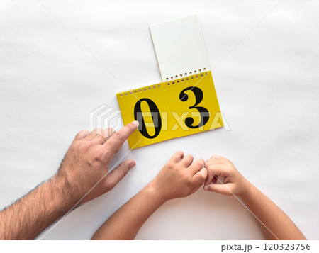 Father and child learning numbers with a yellow flip calendar 120328756