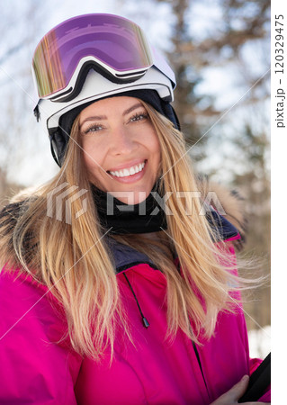 Attractive happy woman model in pink ski suit with skis 120329475