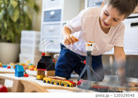 A small white-skinned European child builds a toy railway at home on the carpet. The boy plays A small white-skinned European child builds a toy railway at home on the carpet. The boy plays 120329548