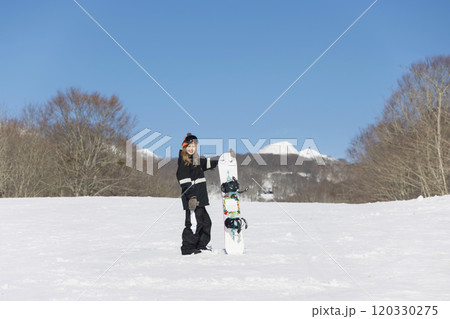 スノボを持ってカメラ目線で立つ若い女性 スノーボードイメージ スノボを持ってカメラ目線で立つ若い女性 スノーボードイメージ 120330275