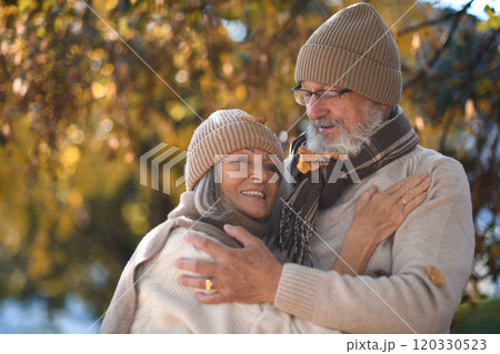 Portrait of beautiful senior couple during walk in autumn park. Elderly husband and wife are embracing each other. 120330523