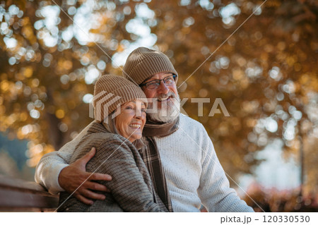 Portrait of beautiful senior couple during walk in autumn park. Elderly husband and wife are embracing each other. 120330530