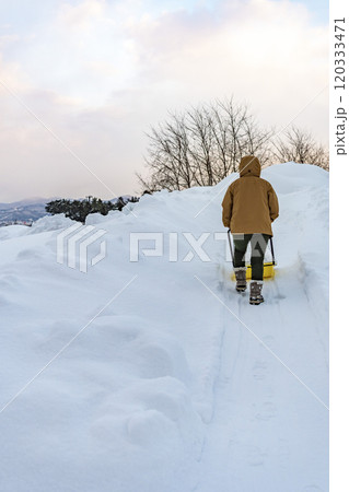 スノーダンプで雪かきをする若い女性 120333471