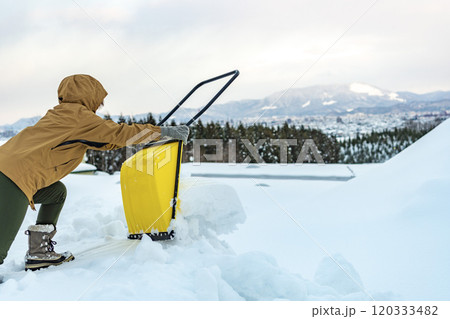 スノーダンプで雪かきをする若い女性 120333482
