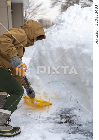 スコップで雪かきをする若い女性 スコップで雪かきをする若い女性 120333493