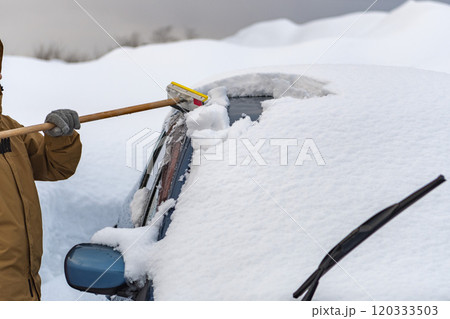車に積もった雪を下ろす女性 車に積もった雪を下ろす女性 120333503