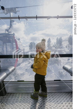 Little boy riding cable car to the top of the mountain during winter holiday with his family. Little boy riding cable car to the top of the mountain during winter holiday with his family. 120333772