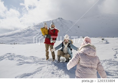 Young family is enjoying winter holiday in the mountains, playing in snow, having fun. 120333804