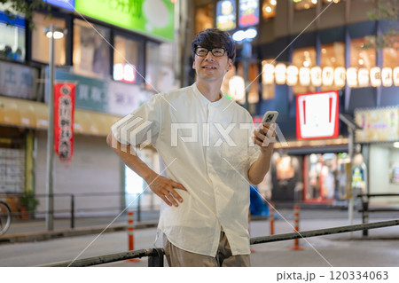 街でスマートフォンを操作する男性 120334063