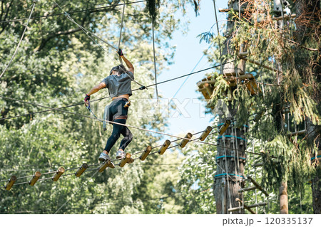 A woman skillfully navigating a challenging tree climbing course while surrounded by vibrant and lush greenery 120335137