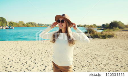 Stylish happy woman standing on beach, looking away, posing on sea coast background 120335533