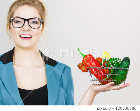 Woman holds shopping basket with vegetables 120336586