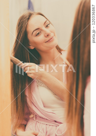 Woman combing her long hair in bathroom Woman combing her long hair in bathroom 120336867