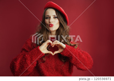 woman in sweater and beret showing heart hands and sending kiss woman in sweater and beret showing heart hands and sending kiss 120336971