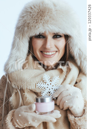 smiling modern woman in winter coat and fur hat on white 120337426