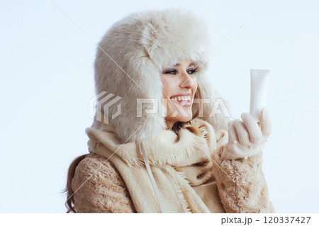 smiling stylish woman in winter coat and fur hat on white 120337427