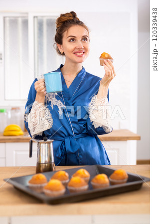 Woman holding mug of fresh coffee and muffins, having hot drink for breakfast 120339438