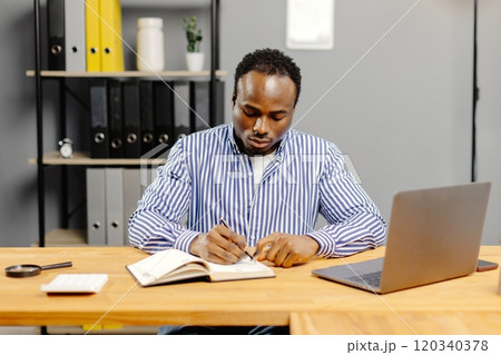 Man sitting at desk holding paper 120340378