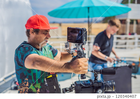 the production team on a commercial video shoot. Steadicam operator uses the 3-axis camera stabilizer and cinema-grade camera the production team on a commercial video shoot. Steadicam operator uses the 3-axis camera stabilizer and cinema-grade camera 120340407