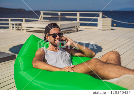 Young man enjoying leisure, lying on the air sofa Lamzac, near the sea Young man enjoying leisure, lying on the air sofa Lamzac, near the sea 120340424