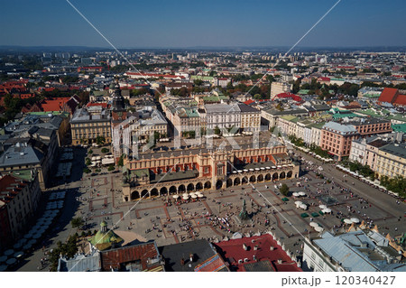 Aerial view of Krakow main market square with historic Cloth Hall (Sukiennice) surrounding colorful buildings on sunny day. Cityscape of Krakow in Poland with tourists walking in old town 120340427