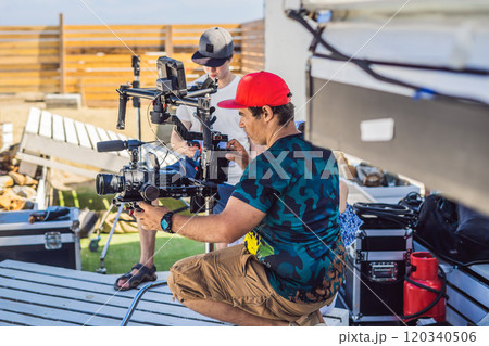 Steadicam operator and his assistant prepare camera and 3-axis stabilizer-gimbal for a commercial shoot 120340506