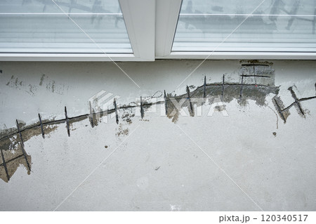 Repairing cracks in concrete floor near window using sealant. Renovation process in house under construction Repairing cracks in concrete floor near window using sealant. Renovation process in house under construction 120340517
