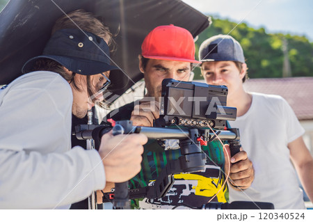 Steadicam operator and his assistant prepare camera and 3-axis stabilizer-gimbal for a commercial shoot Steadicam operator and his assistant prepare camera and 3-axis stabilizer-gimbal for a commercial shoot 120340524