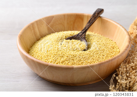 Organic yellow millet grain in wooden bowl with spoon on white table, Healthy food ingredient 120343831